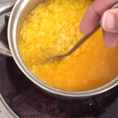 مرحله هم زدن برنج و کم کردن درجه حرارت برای پختن شله زرد